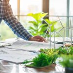 Personne travaillant sur un projet durable, écologique avec des éoliennes de la verdure et de la végétation sur son bureau